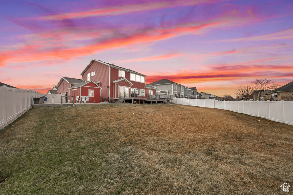 Back house at dusk with a yard and a deck