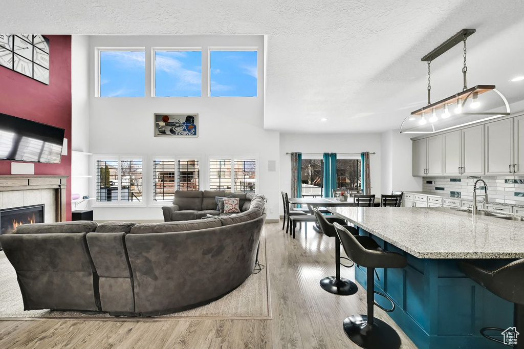 Living room with light hardwood / wood-style floors, sink, a tile fireplace, and a textured ceiling