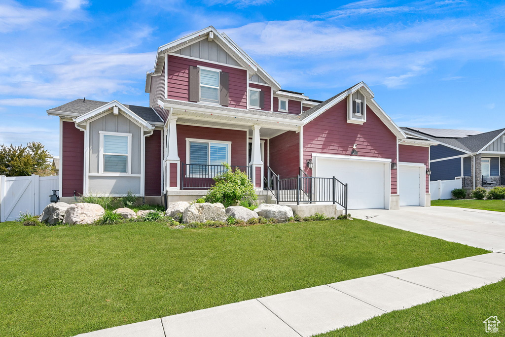 Craftsman-style home with board and batten siding, driveway, fence, and covered porch