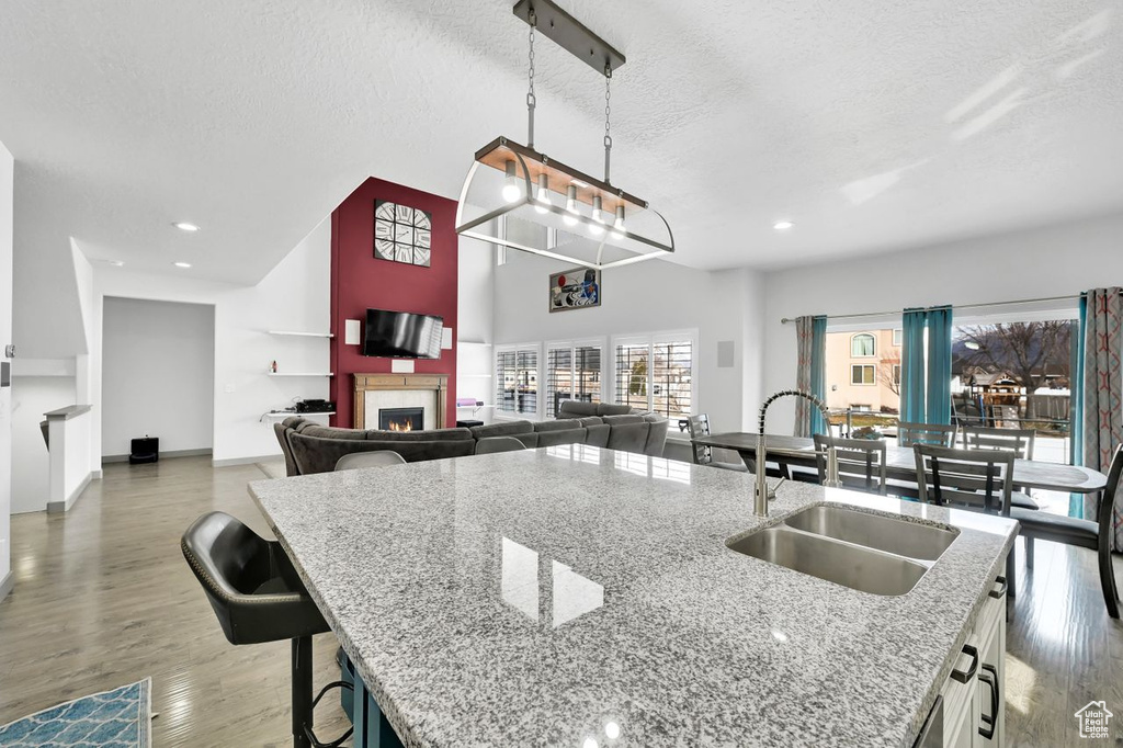 Kitchen featuring light stone counters, sink, hanging light fixtures, and white cabinets