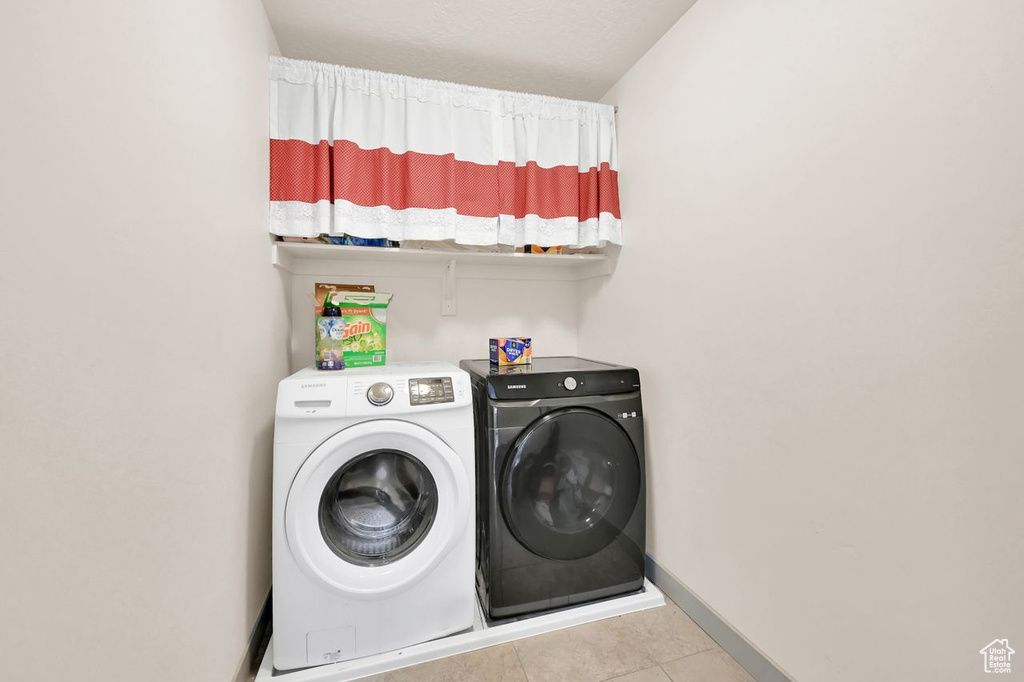 Laundry area with separate washer and dryer and light tile patterned floors