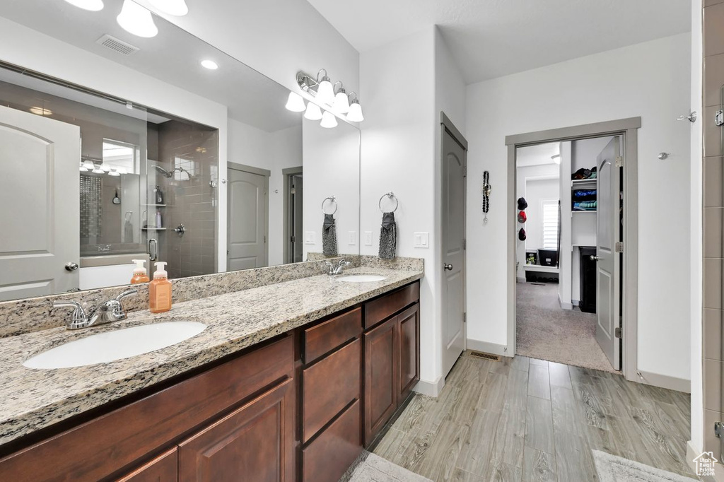 Bathroom with vanity, hardwood / wood-style floors, and a shower with shower door