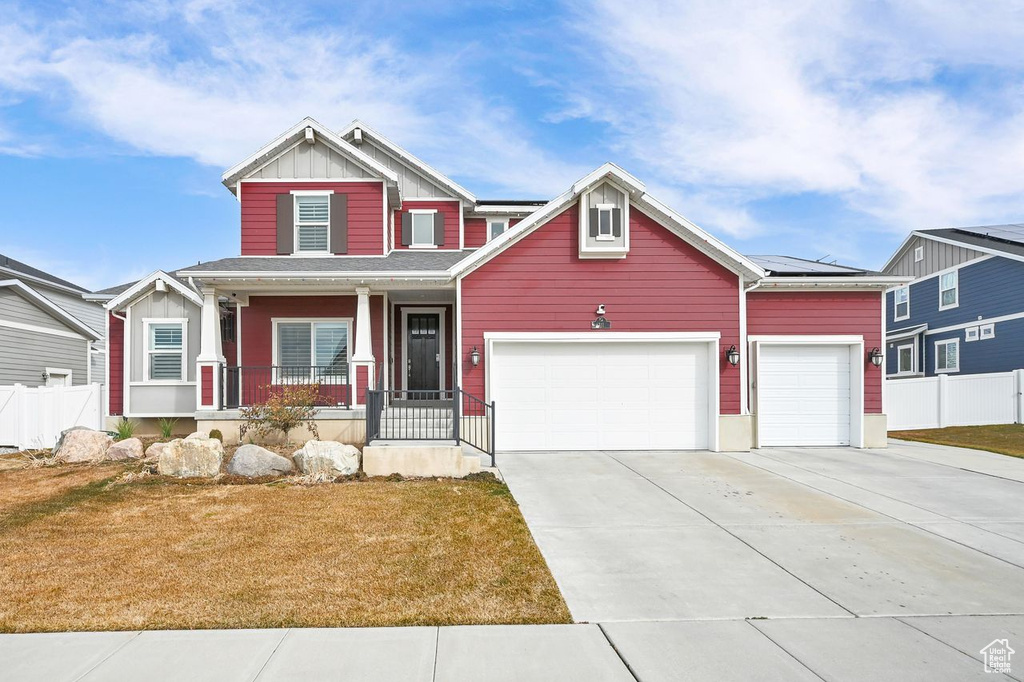 Craftsman-style home featuring a garage, a front yard, covered porch, and solar panels