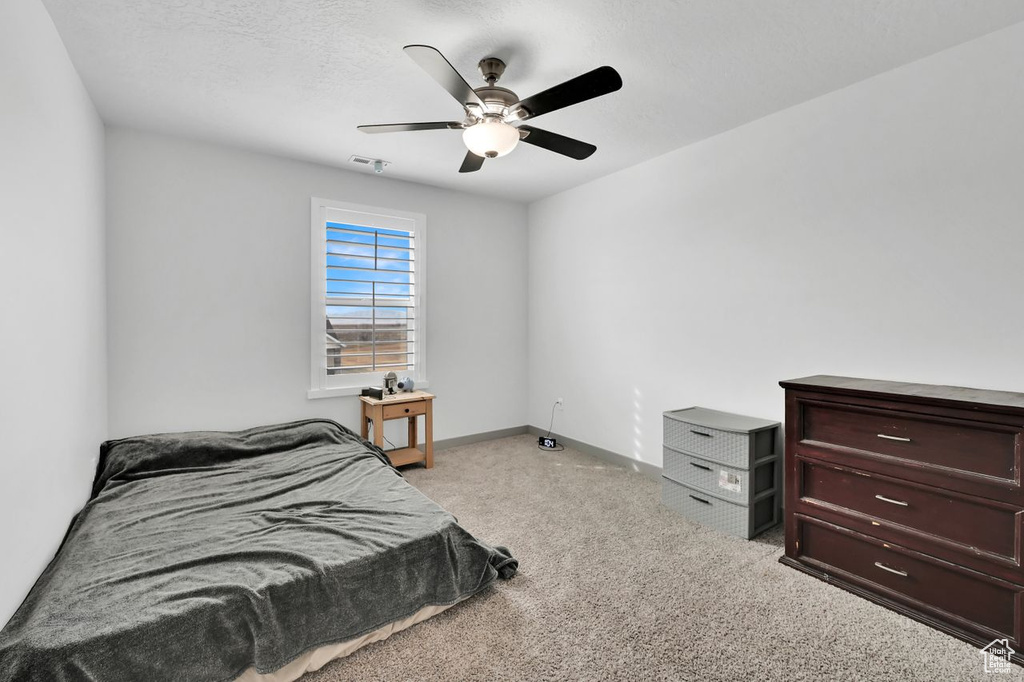 Bedroom with ceiling fan, light colored carpet, and a textured ceiling