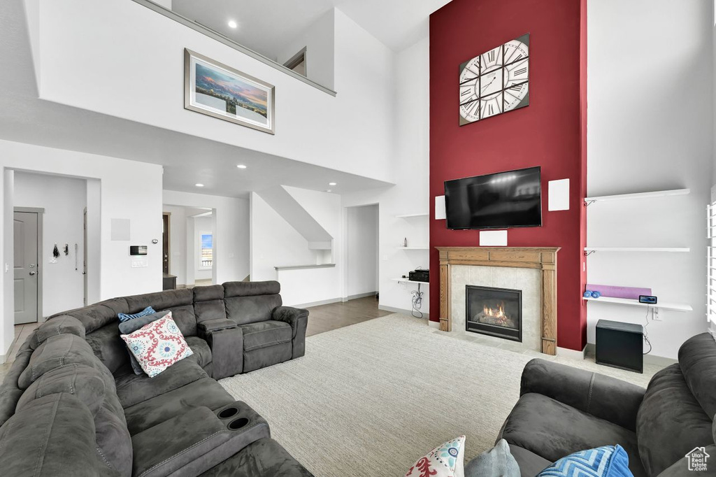 Living room featuring wood-type flooring, a towering ceiling, and a high end fireplace