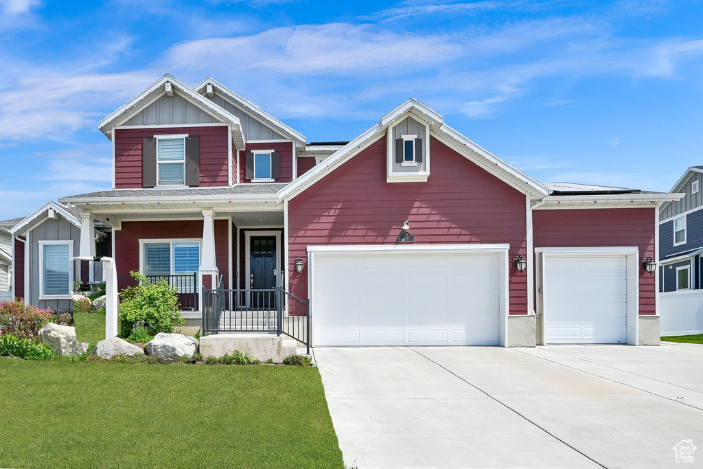 Craftsman inspired home with a porch, board and batten siding, driveway, a front yard, and an attached garage