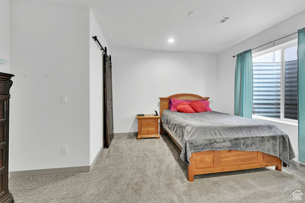 Bedroom featuring a barn door and carpet flooring