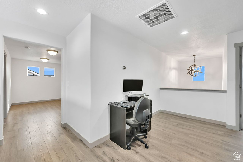 Office space with a chandelier and light hardwood / wood-style flooring