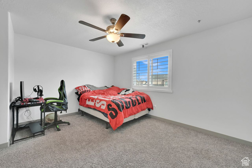 Carpeted bedroom with ceiling fan and a textured ceiling