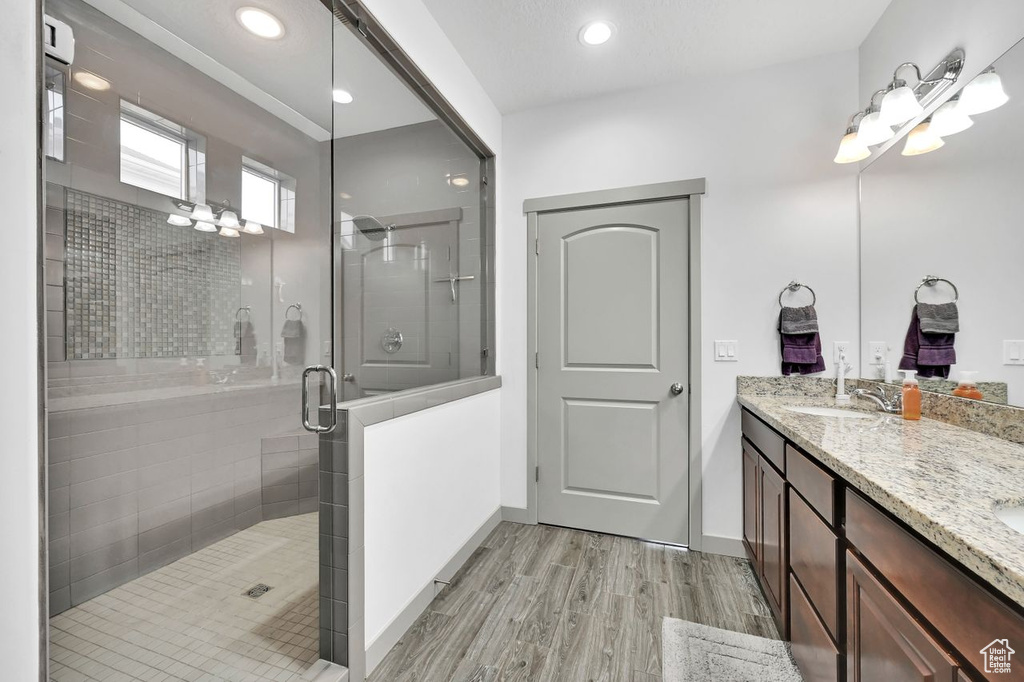 Bathroom with hardwood / wood-style flooring, vanity, and a shower with shower door