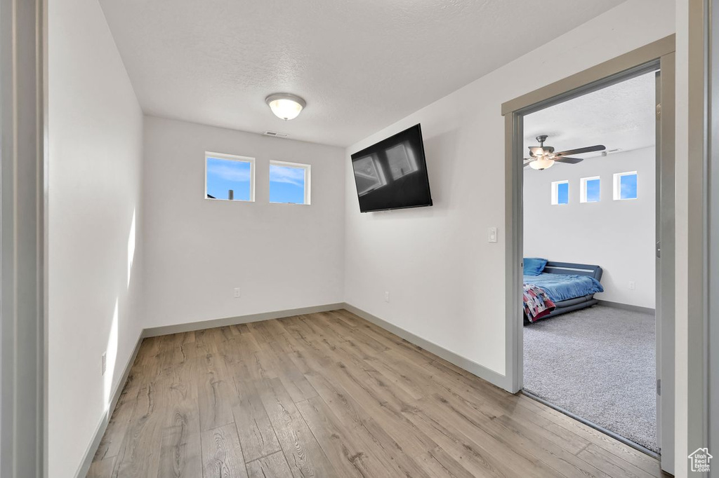 Unfurnished room featuring ceiling fan, a textured ceiling, and light wood-type flooring