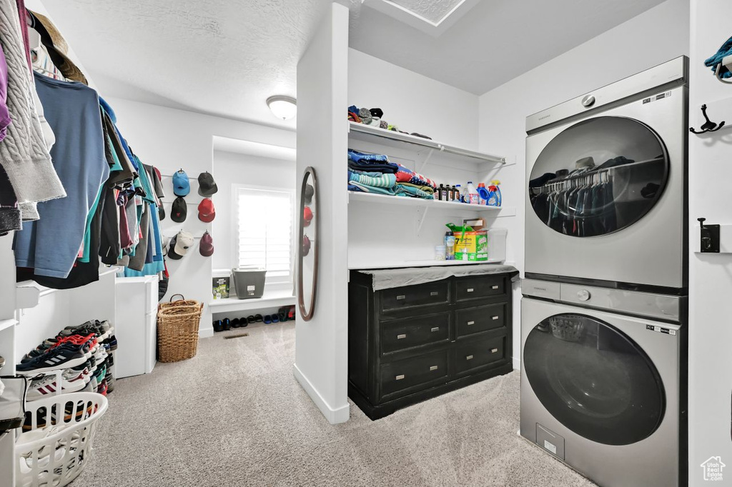 Laundry area with stacked washer / drying machine, carpet floors, and a textured ceiling