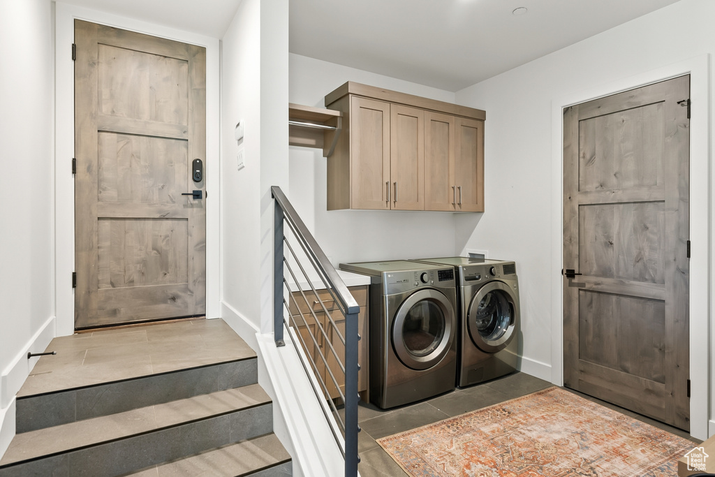 Laundry area with baseboards, light tile patterned floors, washer and dryer, and cabinet space