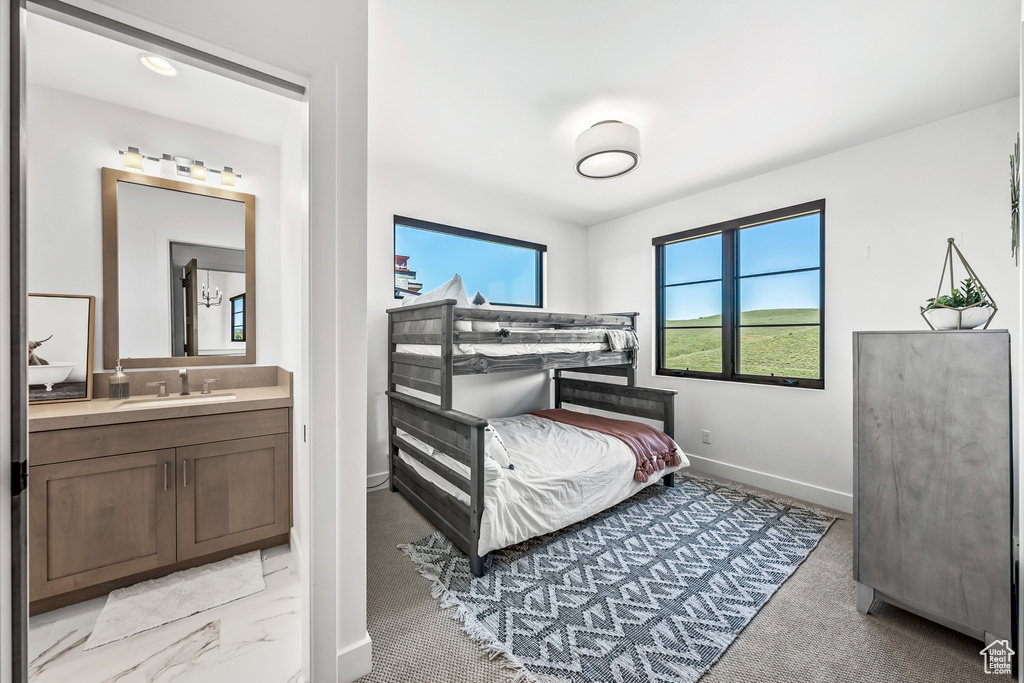 Bedroom featuring baseboards, ensuite bathroom, and a sink
