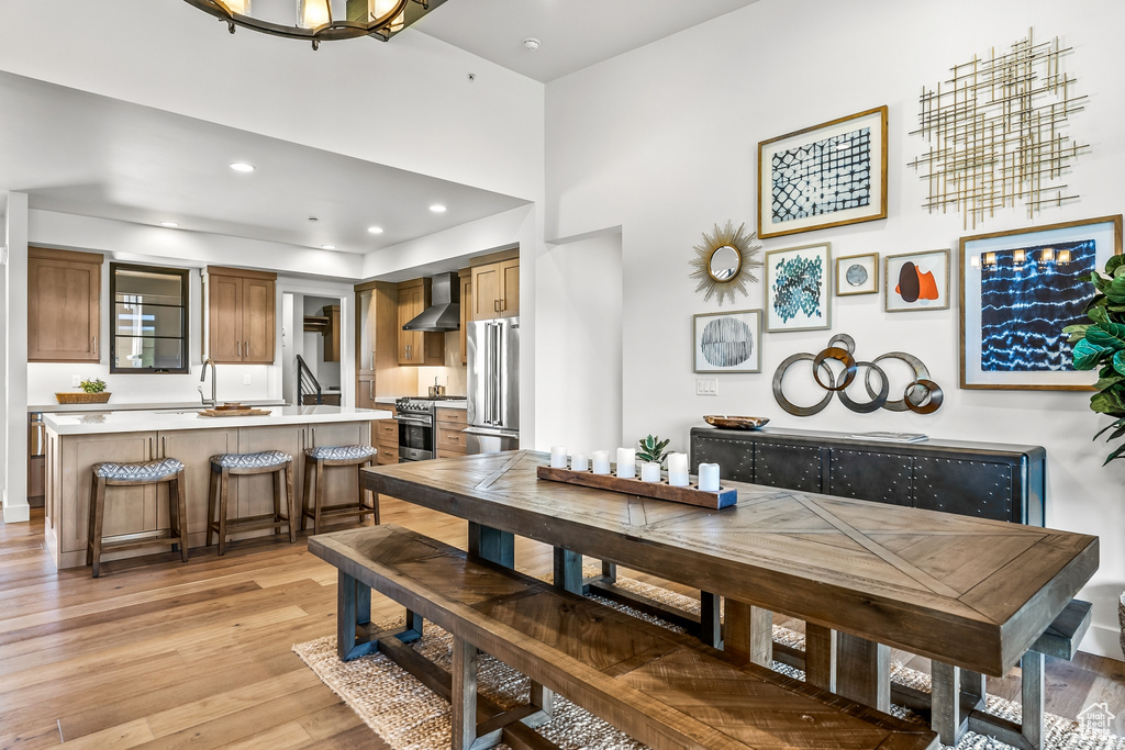 Dining room with a towering ceiling, recessed lighting, and light wood-style flooring