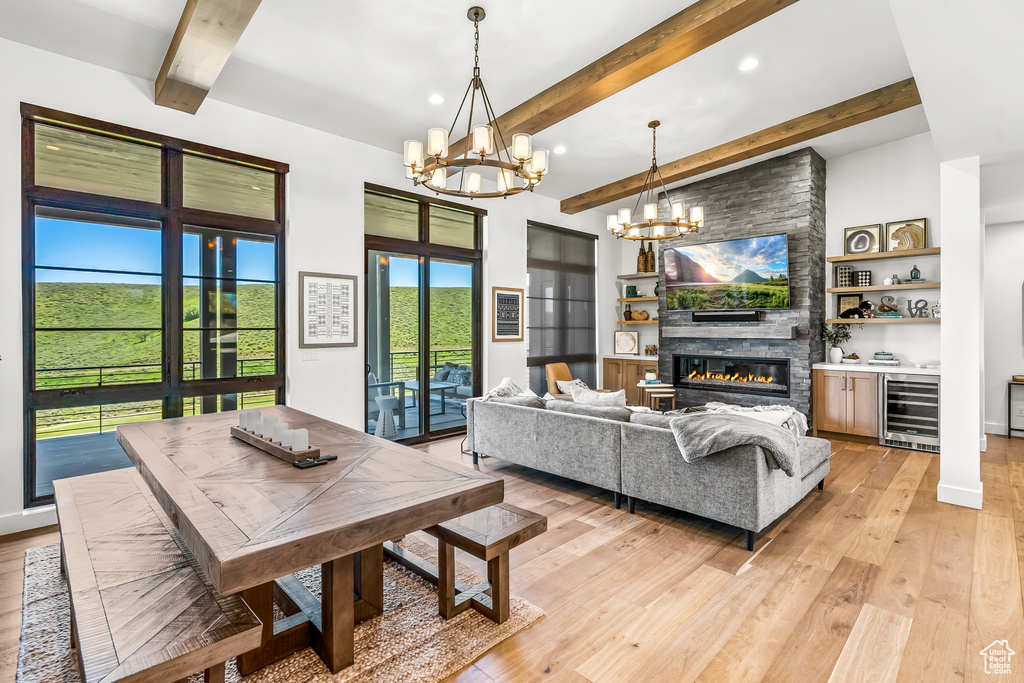 Living room with an inviting chandelier, wine cooler, light wood finished floors, and beamed ceiling