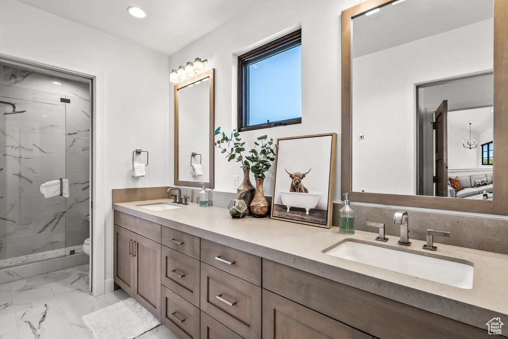 Full bathroom featuring a marble finish shower, marble finish floor, double vanity, and a sink