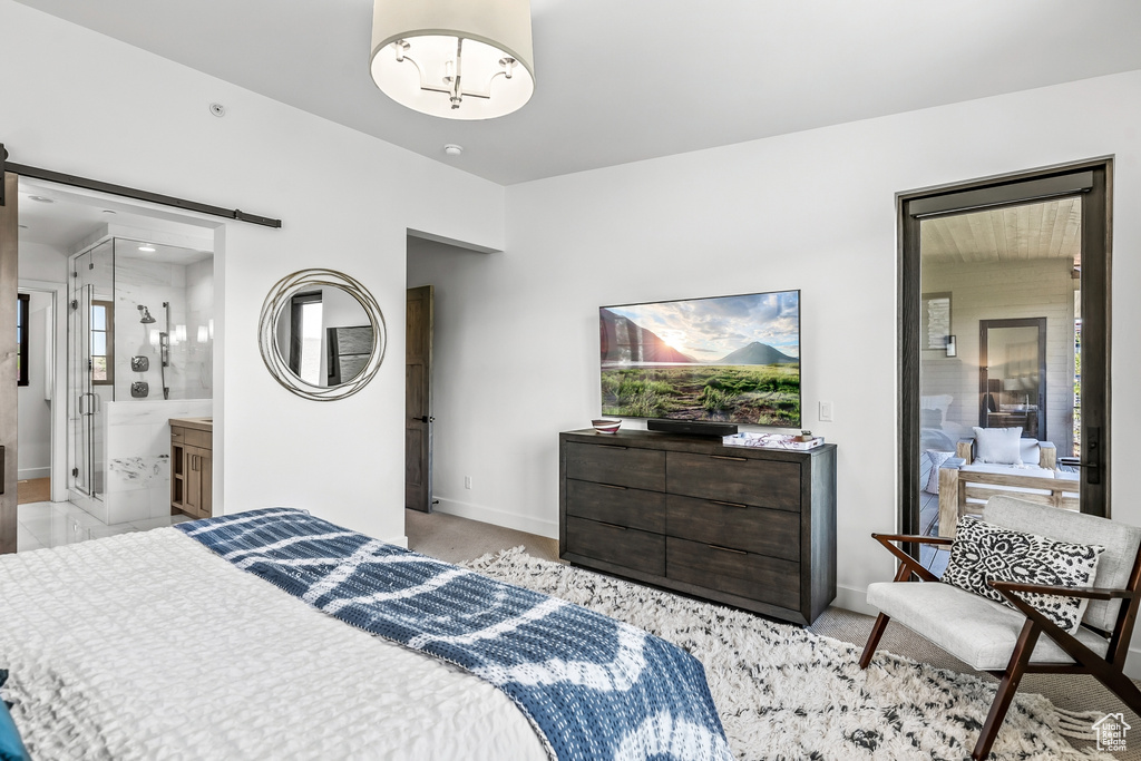 Bedroom with baseboards, a barn door, connected bathroom, and multiple windows