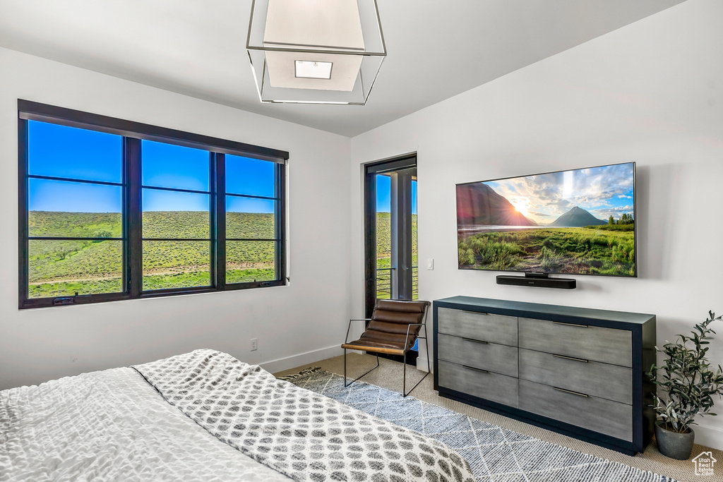 Bedroom featuring light colored carpet, access to exterior, and baseboards