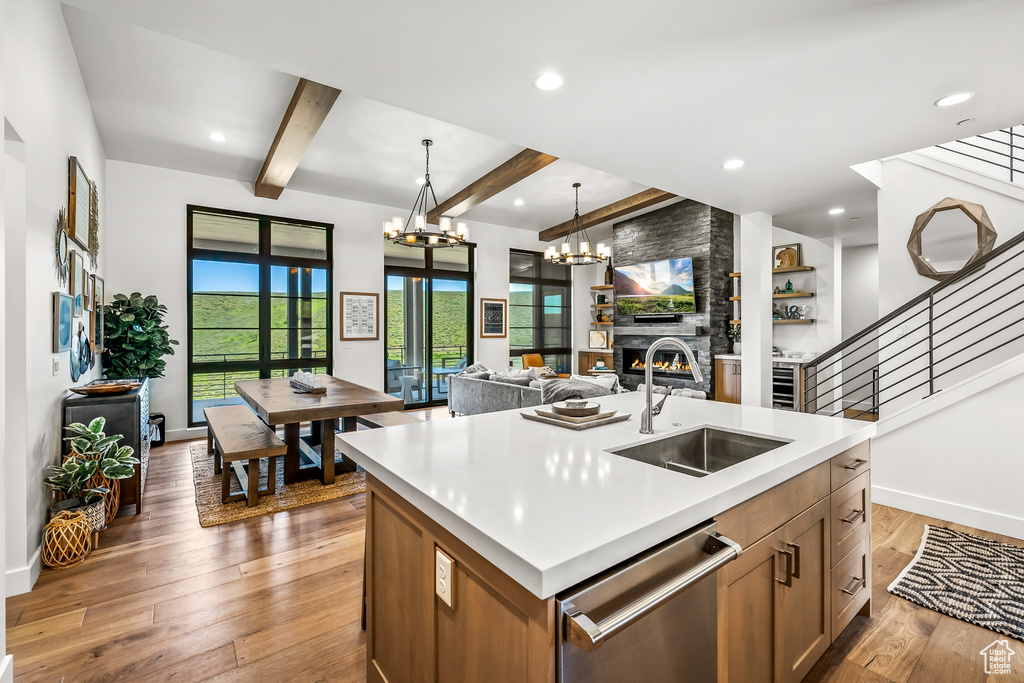 Kitchen featuring hardwood / wood-style flooring, beamed ceiling, a sink, open floor plan, and dishwasher