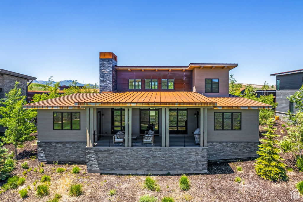 Rear view of property featuring a standing seam roof, metal roof, a patio, and a chimney