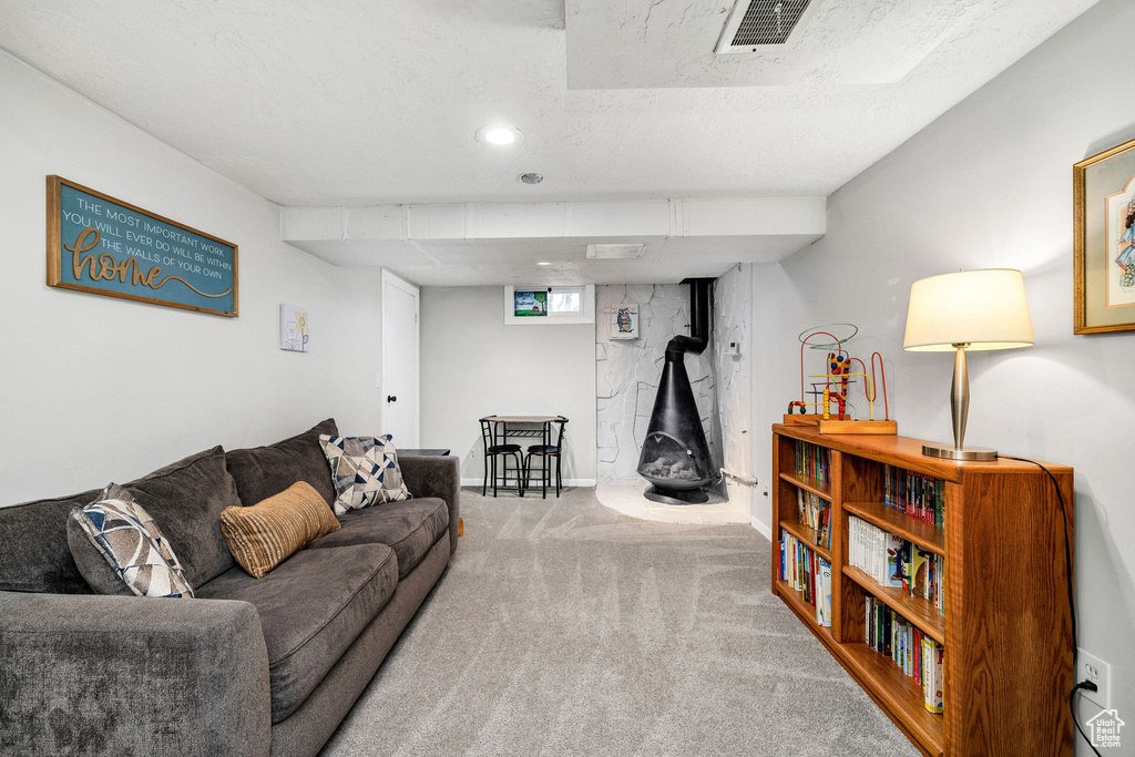 Living room featuring carpet floors, a wood stove, and a textured ceiling