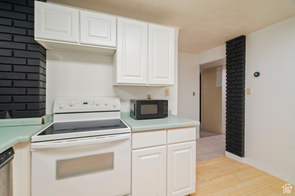 Kitchen with stainless steel dishwasher, white electric range oven, white cabinets, and light hardwood / wood-style floors