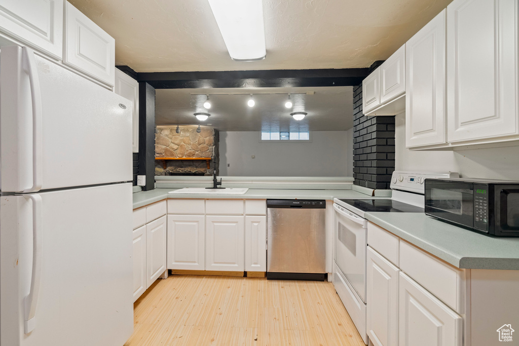 Kitchen featuring white cabinetry, sink, light hardwood / wood-style floors, kitchen peninsula, and white appliances