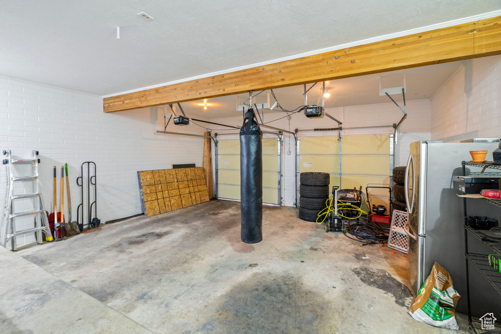 Garage with stainless steel refrigerator and a garage door opener
