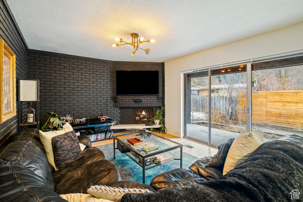 Living room with an inviting chandelier, wood-type flooring, a fireplace, and a textured ceiling