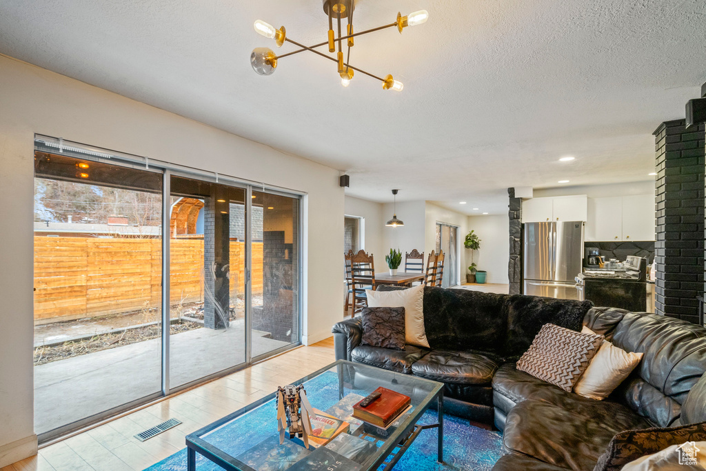 Living room featuring light wood-type flooring, a notable chandelier, and a textured ceiling