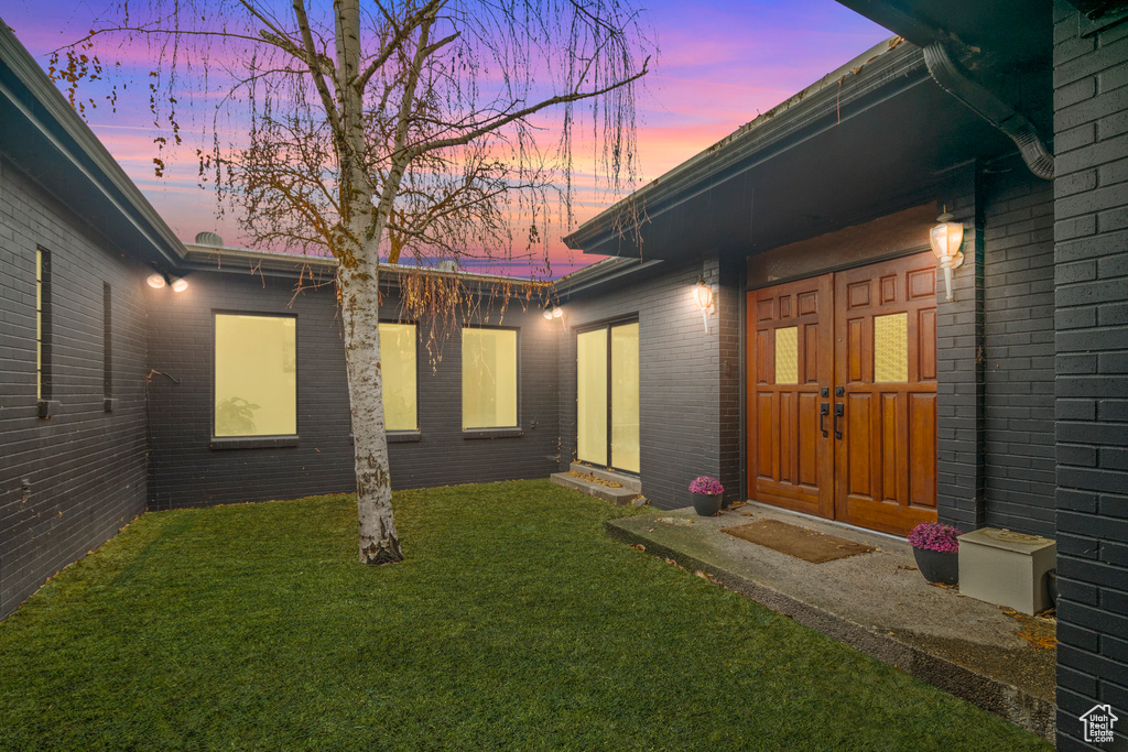 Exterior entry at dusk with a lawn