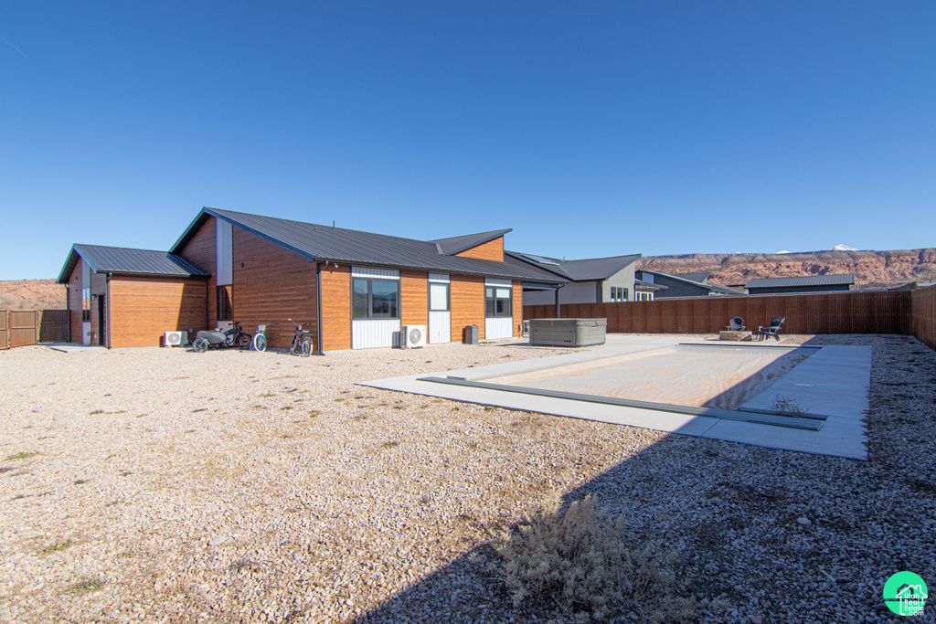 Back of house featuring a hot tub and a patio