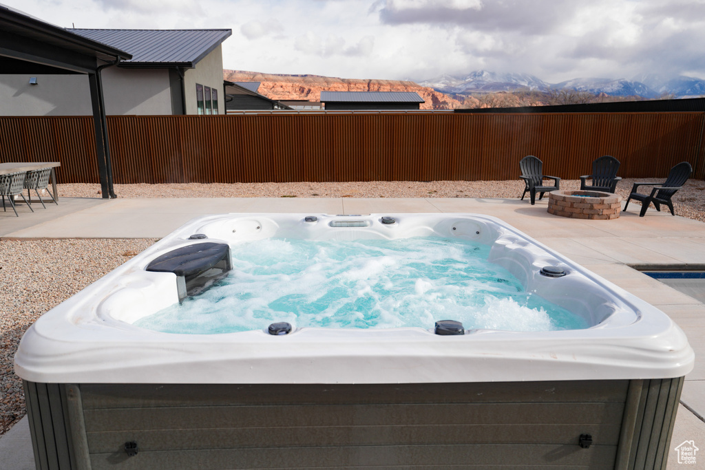 View of pool featuring a mountain view, a fire pit, a patio area, and a hot tub