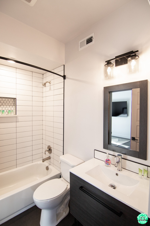 Full bathroom featuring vanity, tiled shower / bath combo, and toilet