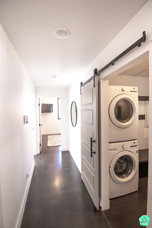 Laundry room featuring stacked washer and clothes dryer and a barn door