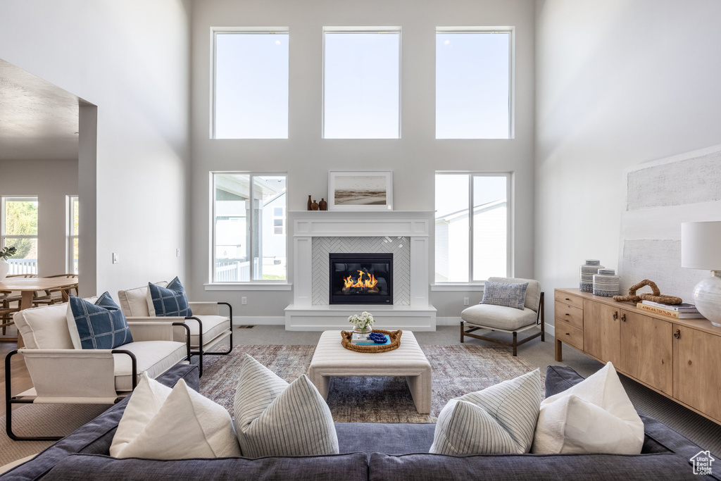 Living room featuring carpet flooring, a high ceiling, a tile fireplace, and healthy amount of natural light