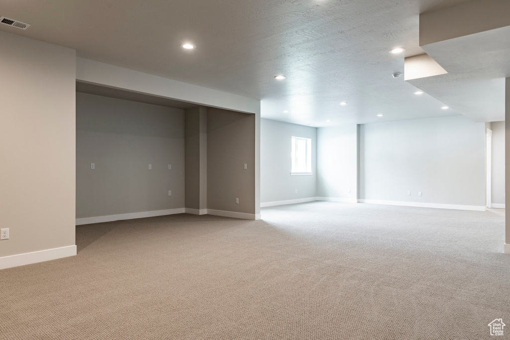 Below grade area featuring light colored carpet, recessed lighting, and baseboards