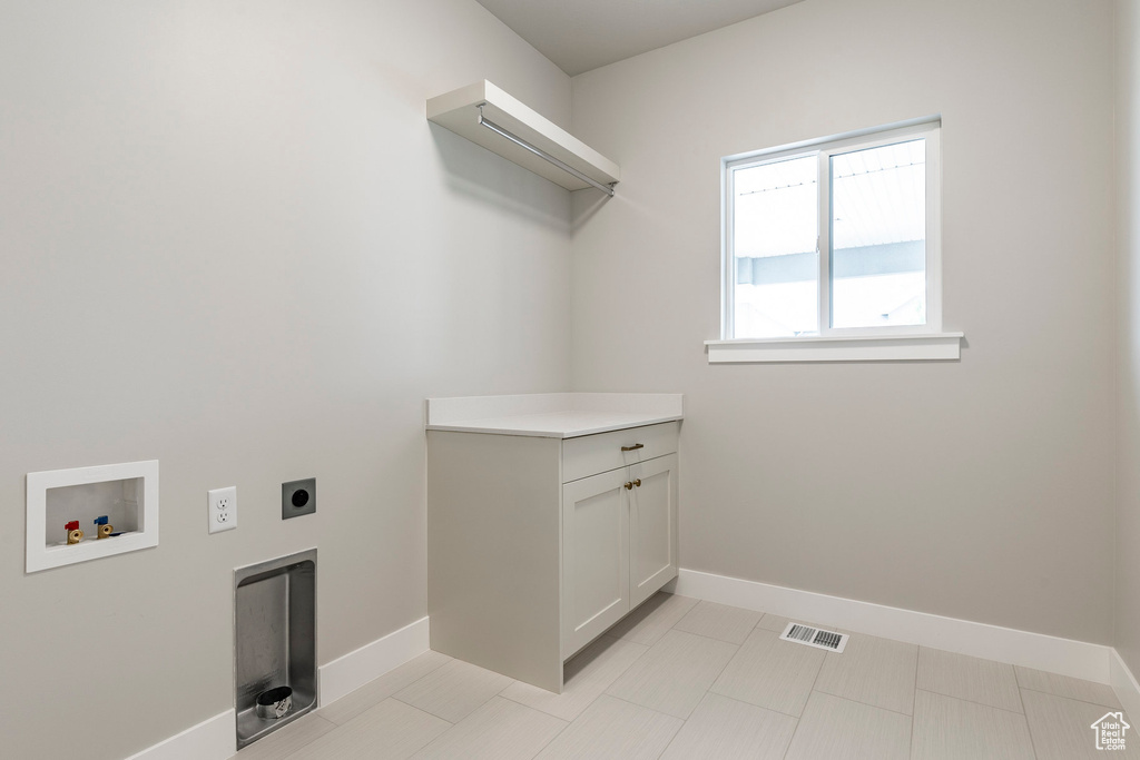 Washroom featuring hookup for an electric dryer, hookup for a washing machine, baseboards, and cabinet space