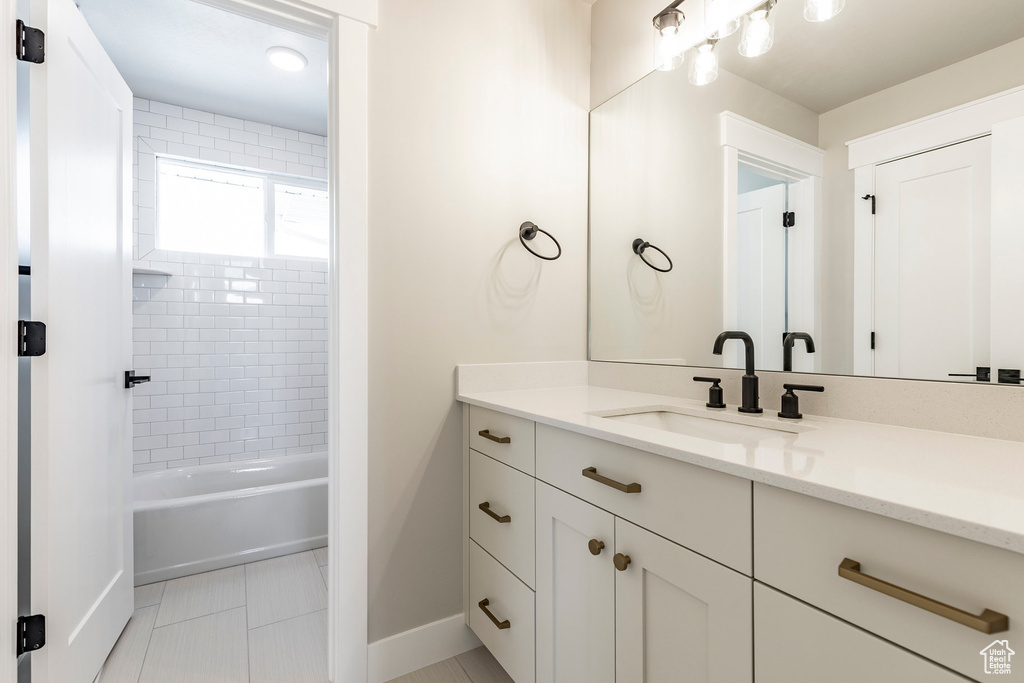Bathroom featuring baseboards, vanity, shower / bath combination, and tile patterned flooring