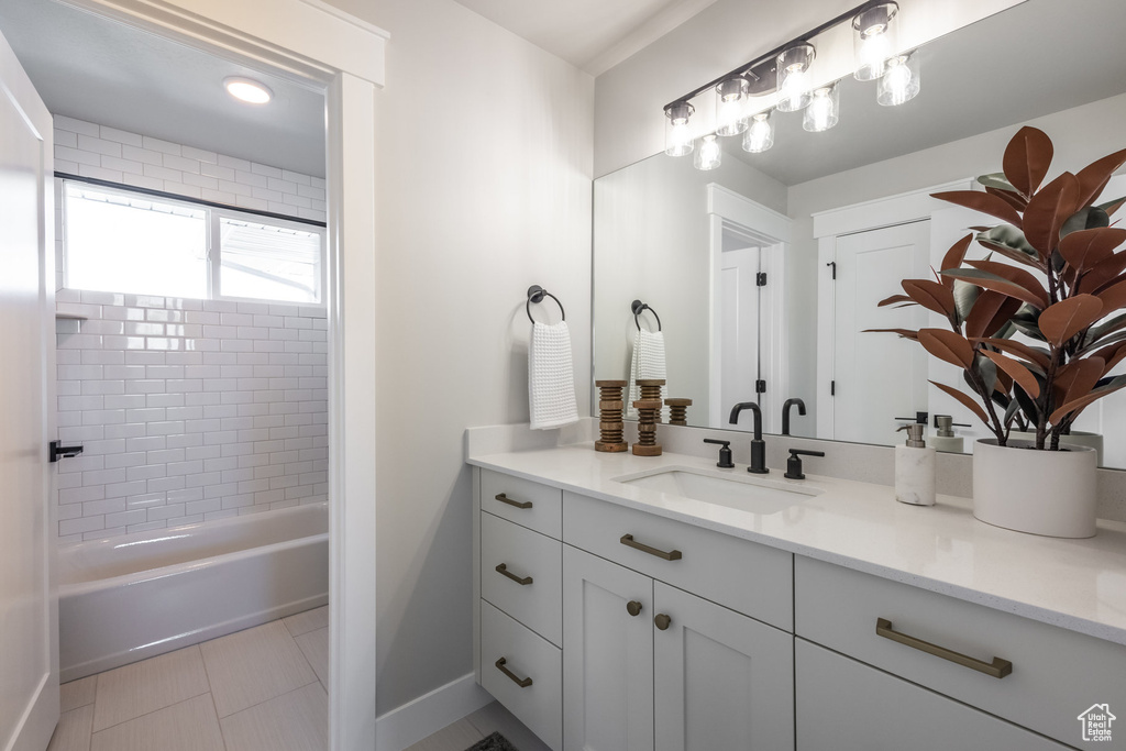 Bathroom with vanity, baseboards, tile patterned flooring, and shower / washtub combination
