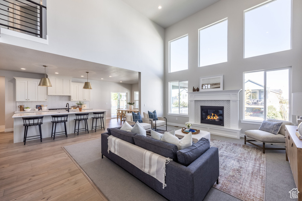 Living area with a high ceiling, light wood finished floors, a tile fireplace, and recessed lighting