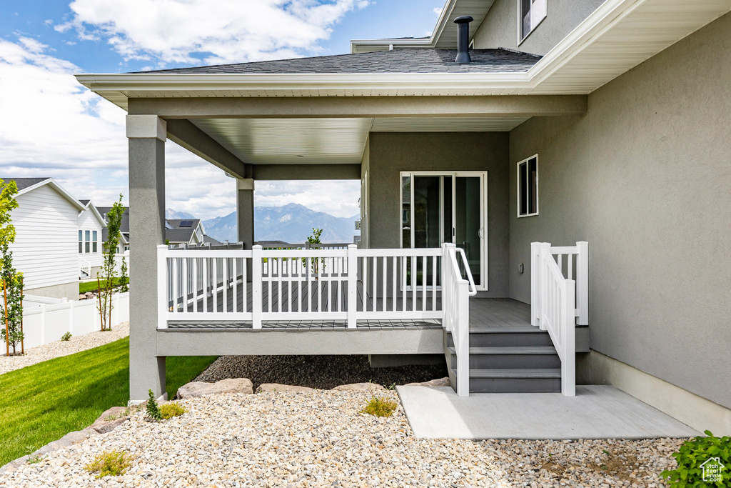 View of exterior entry with fence, stucco siding, and a deck with mountain view