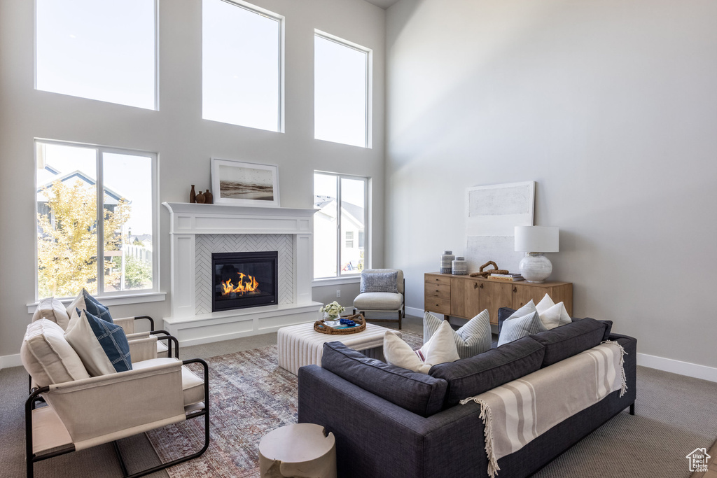 Living area with carpet flooring, a fireplace, baseboards, and a high ceiling