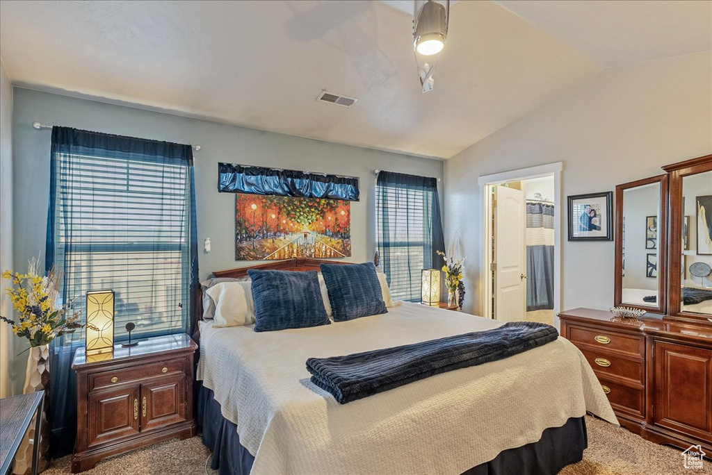 Carpeted bedroom with lofted ceiling, connected bathroom, and ceiling fan