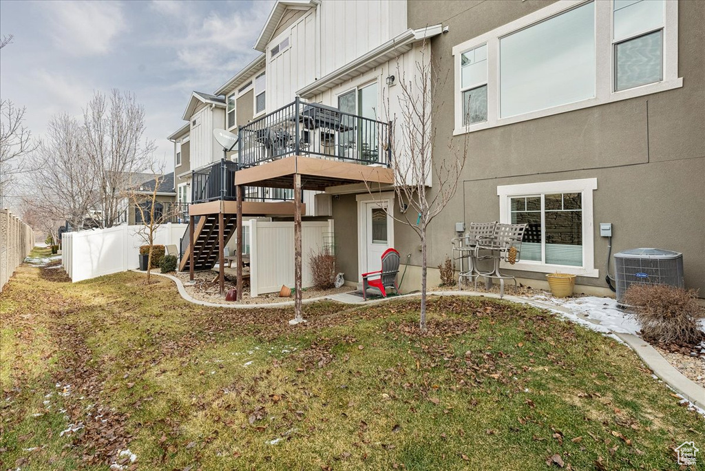 Back of house with a yard, a deck, and central air condition unit