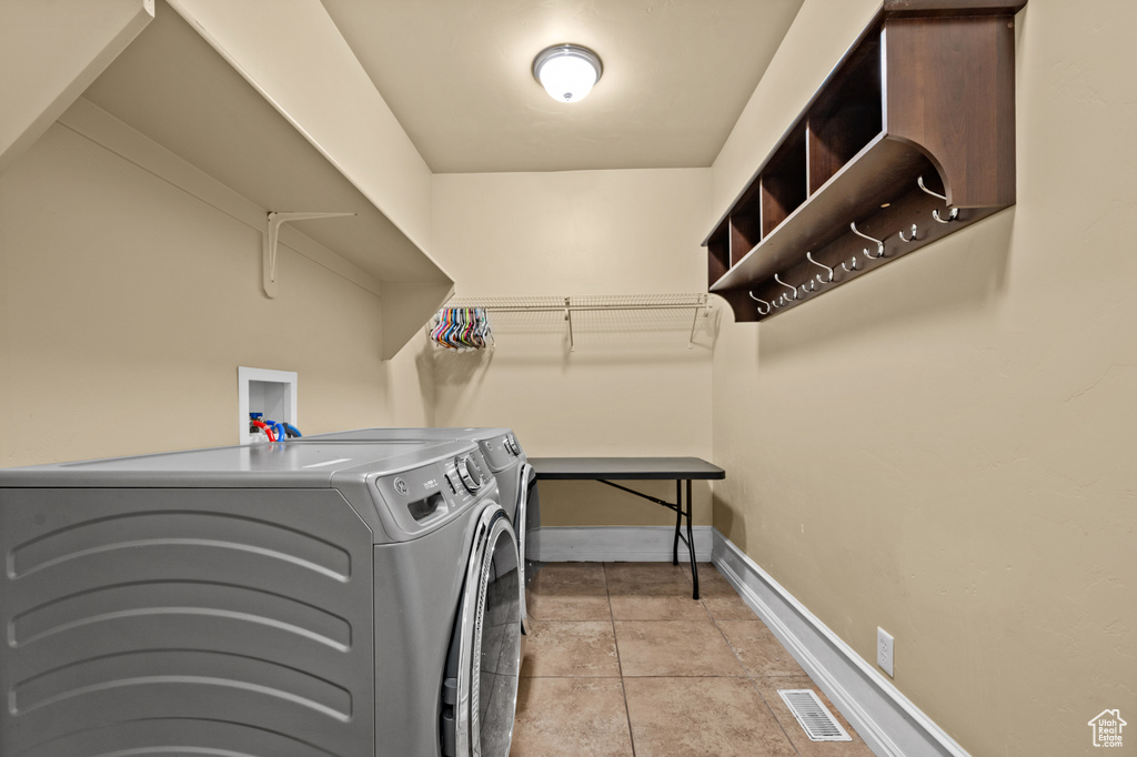 Clothes washing area with separate washer and dryer and light tile patterned floors