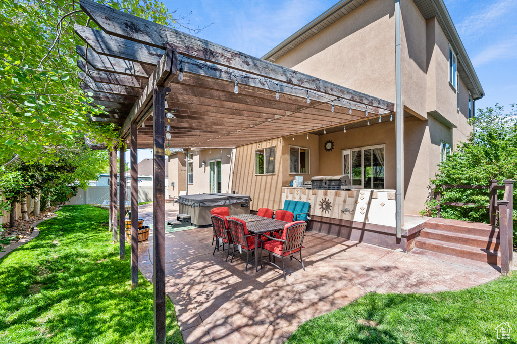 View of patio / terrace featuring a pergola, a hot tub, fence, exterior kitchen, and outdoor dining area