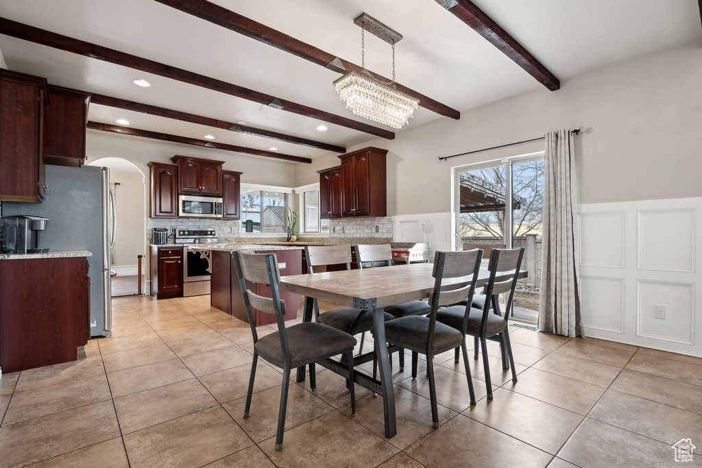 Tiled dining space with plenty of natural light, an inviting chandelier, and beam ceiling