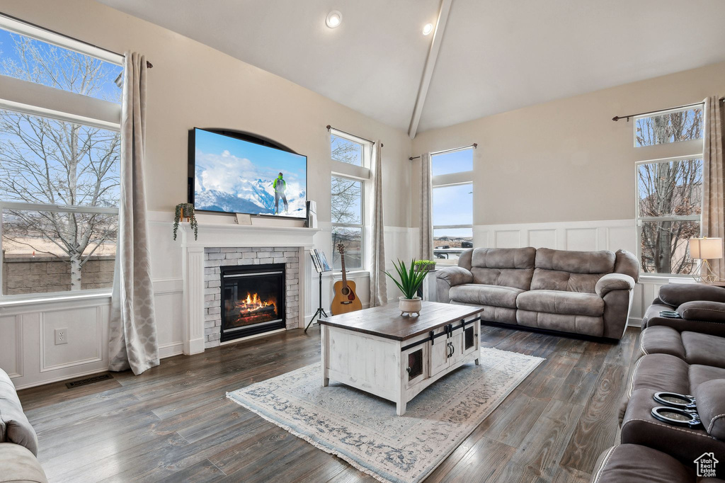 Living room with a brick fireplace, high vaulted ceiling, and dark hardwood / wood-style flooring